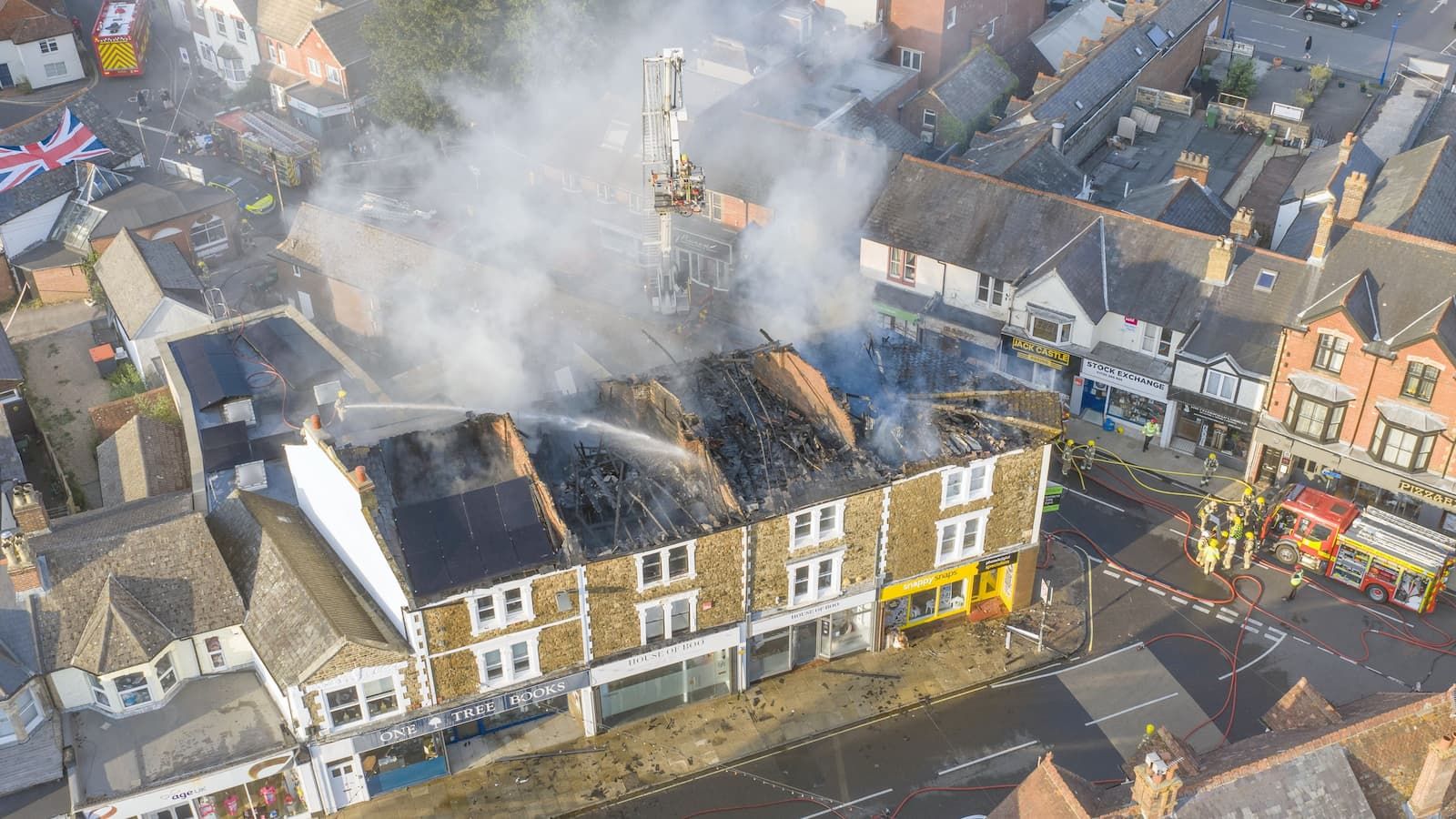 An aerial view of the entire top floor of a row of shops and flats on fire on July 3,2025 in Petersfield, England