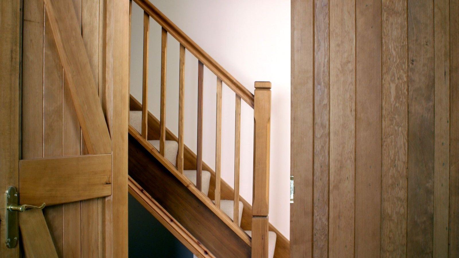 A wooden staircase with wooden door and wooden panelling
