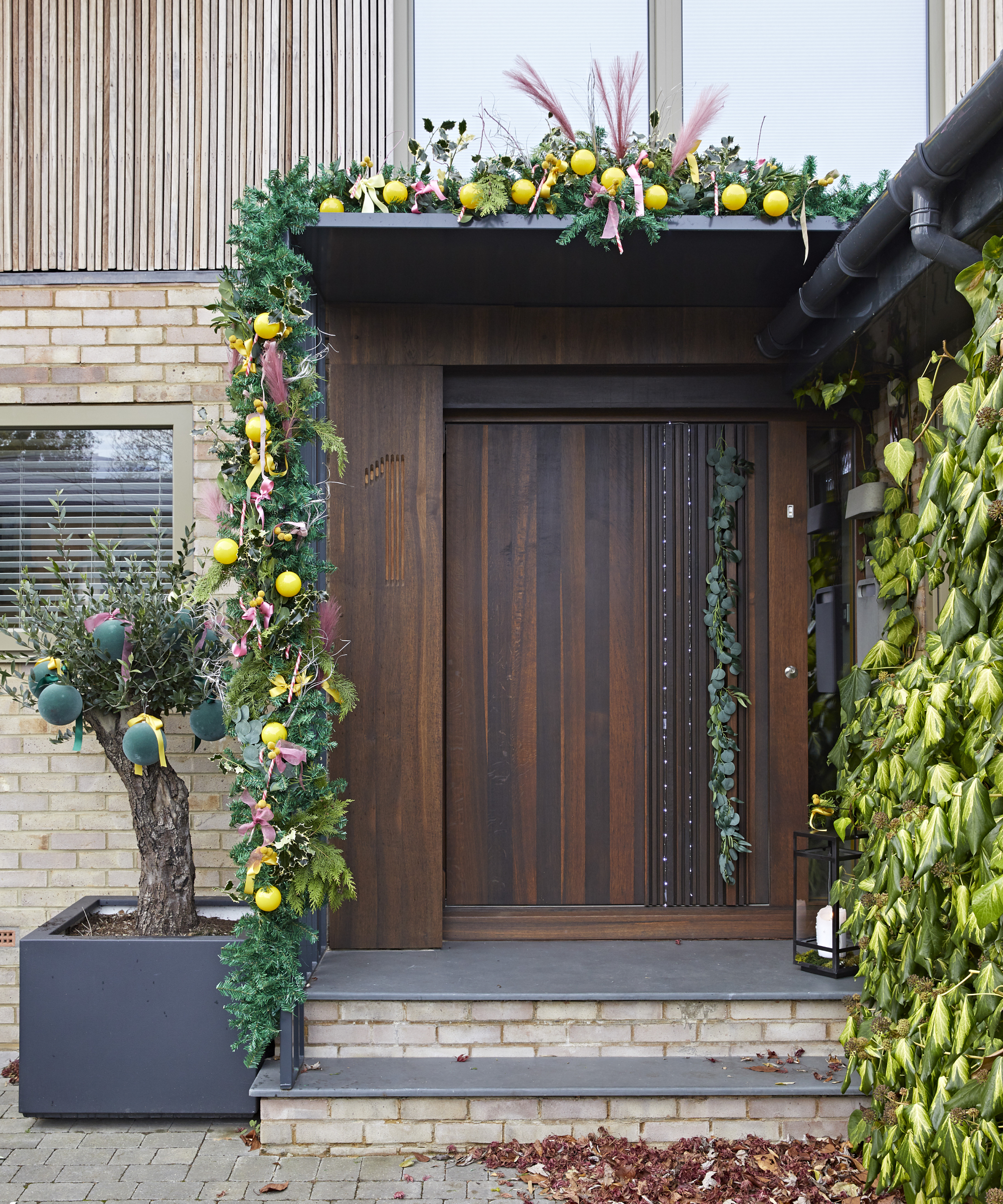 large walnut front door with festive doorscape around canopy and porch
