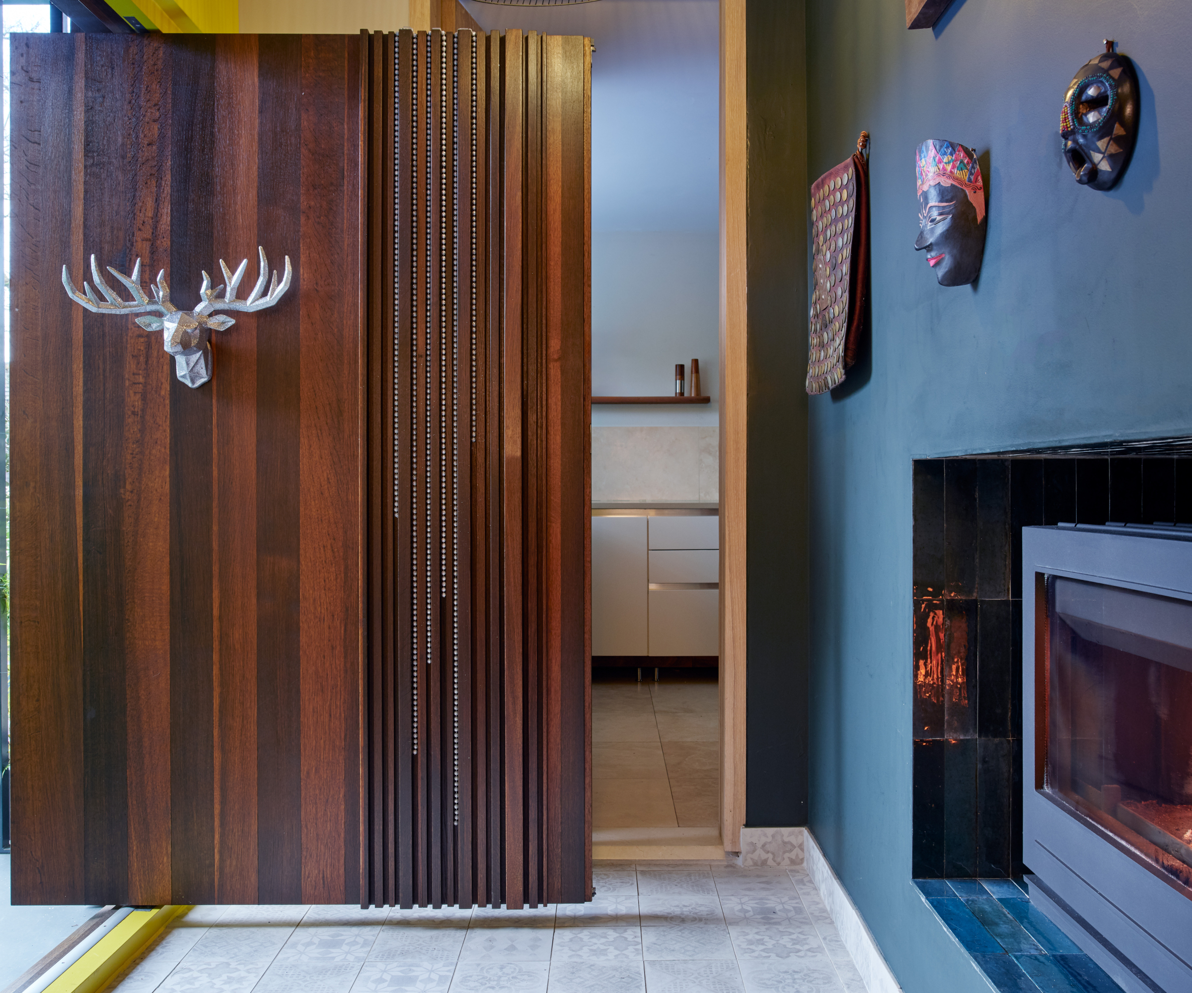 large dark walnut front door with silver stag head and decor hung to side of walnut door strips