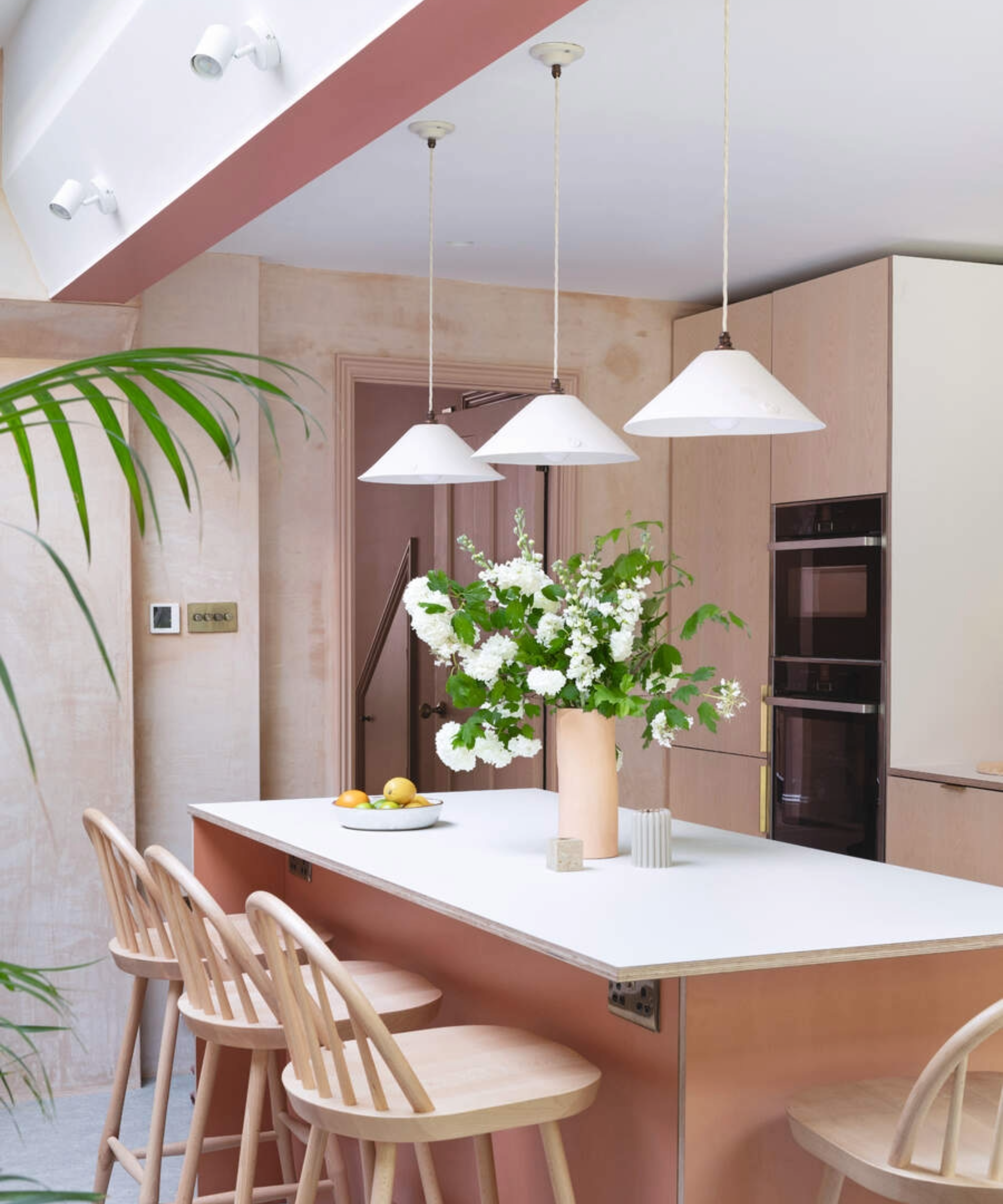 Kitchen with pink accent ceiling and pink island with hanging lights