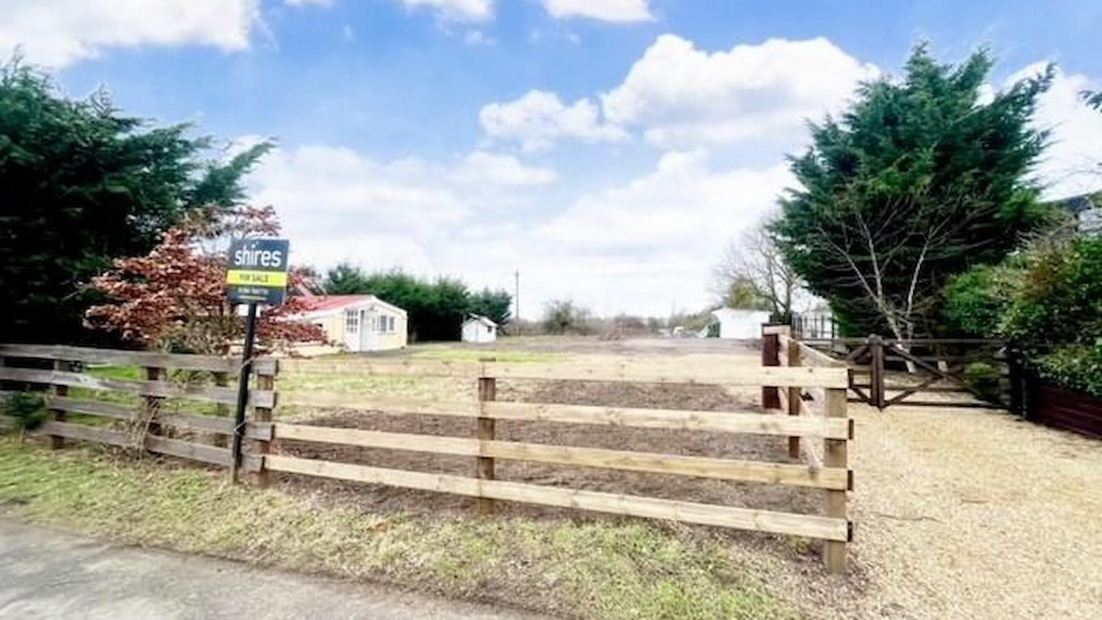 A plot with a wooden gate and gravelled driveway