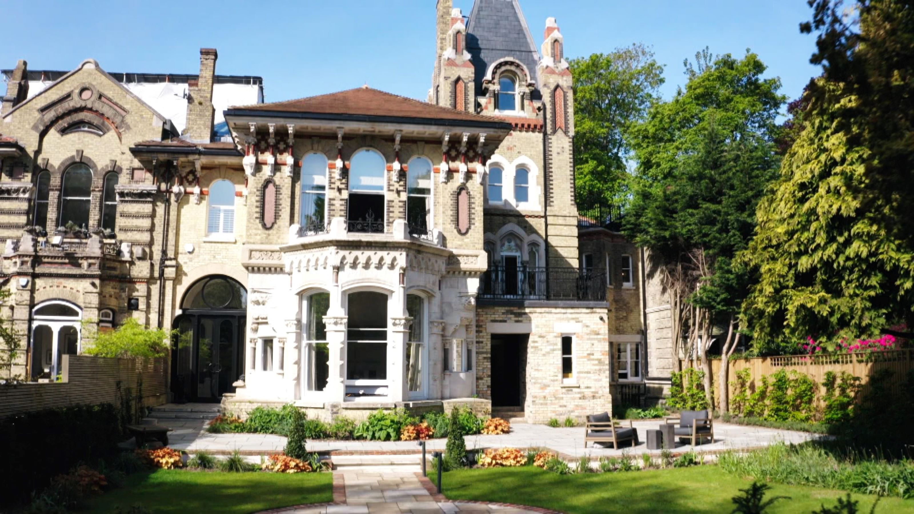 A brick build mansion with a tower to the rear of the property and a balcony