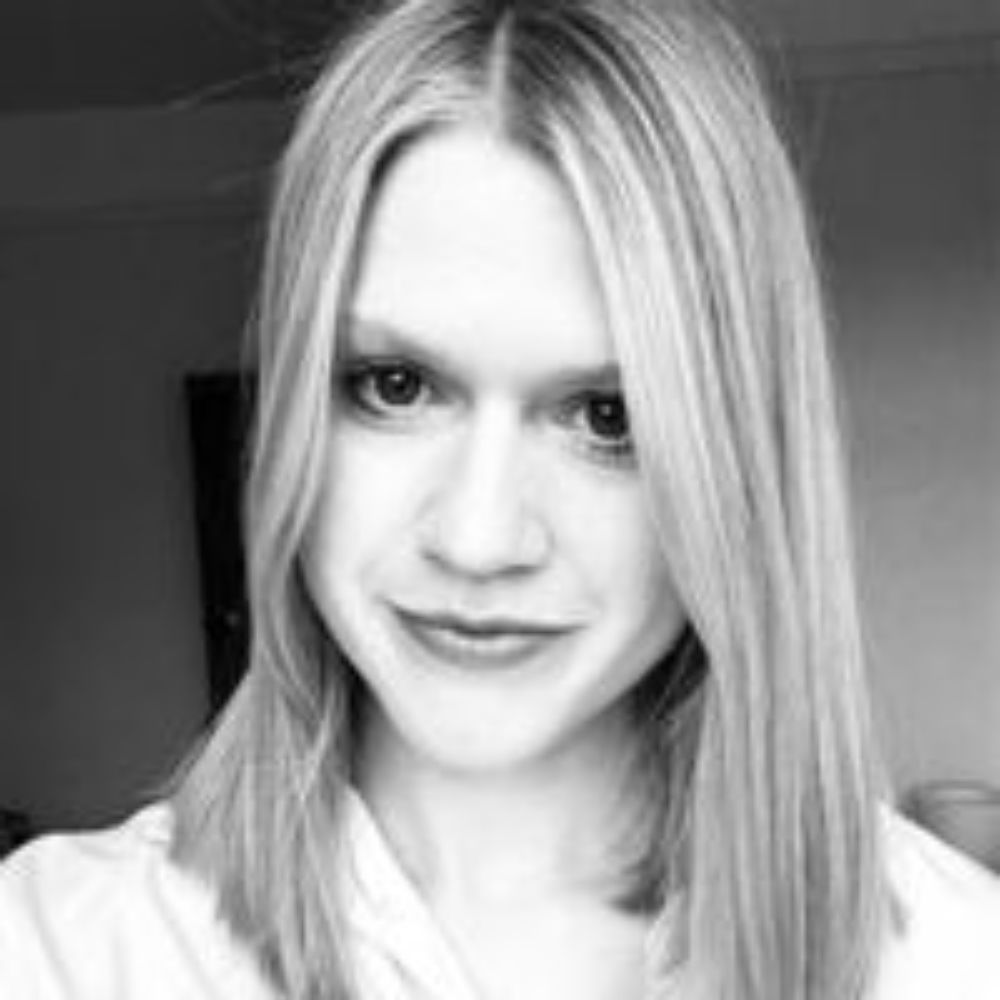 Black and white headshot of a blonde woman smiling at the camera 