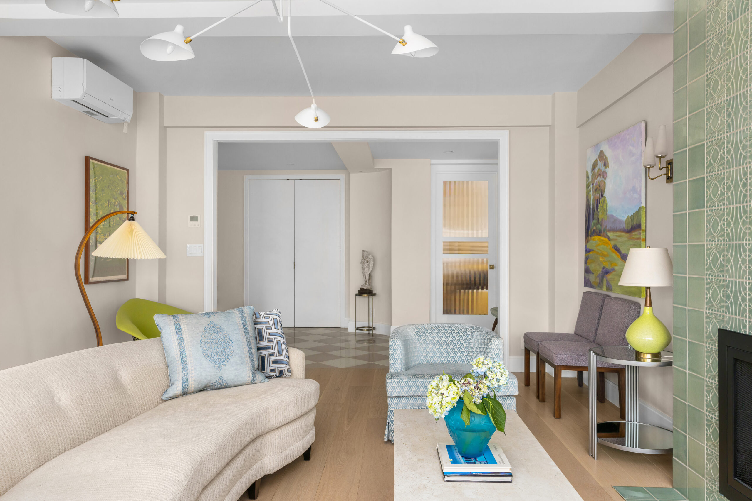 A refined living room with pastel tones, soft seating, and an elegant tiled fireplace after renovation completion.