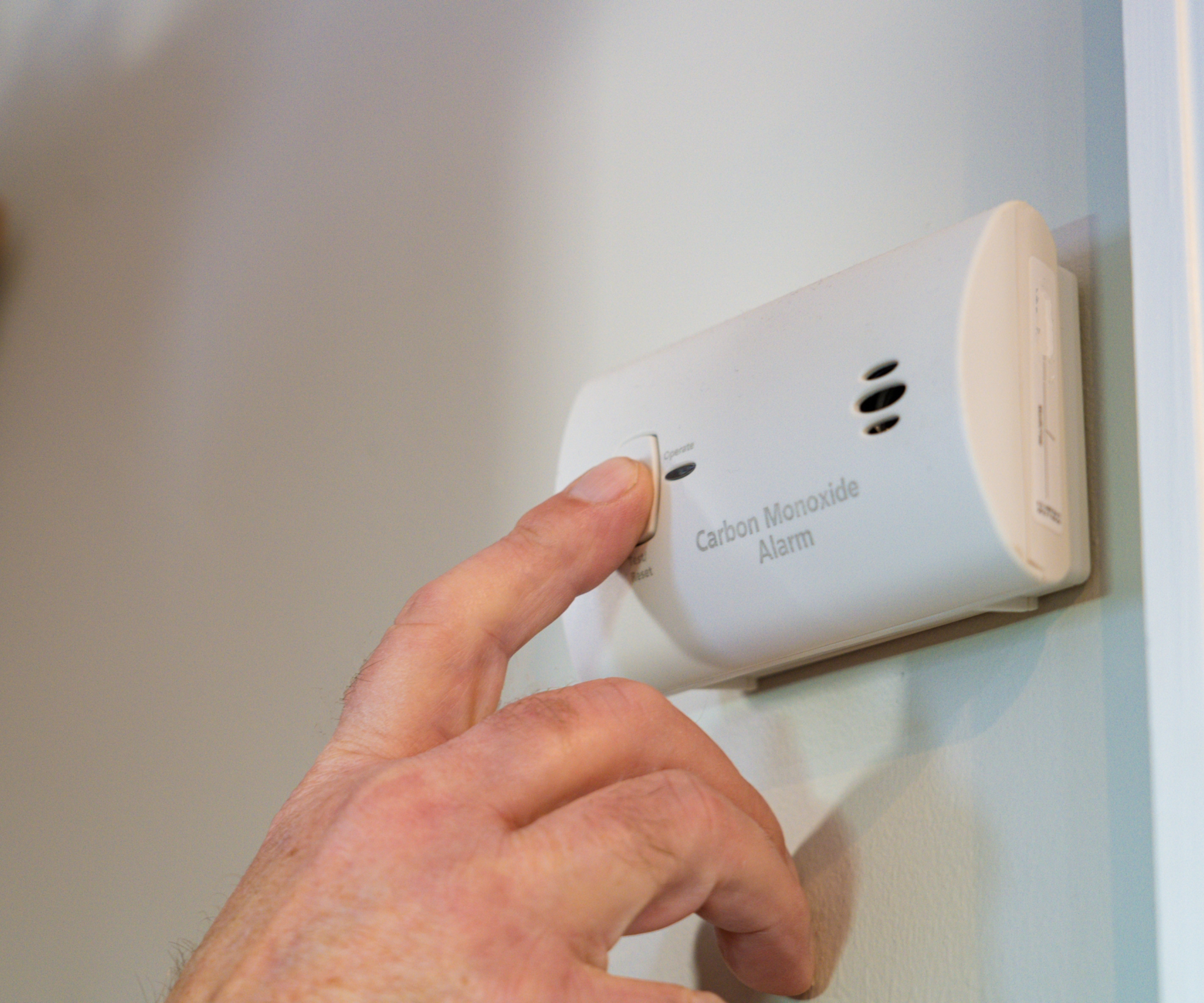 Finger pressing a carbon monoxide alarm
