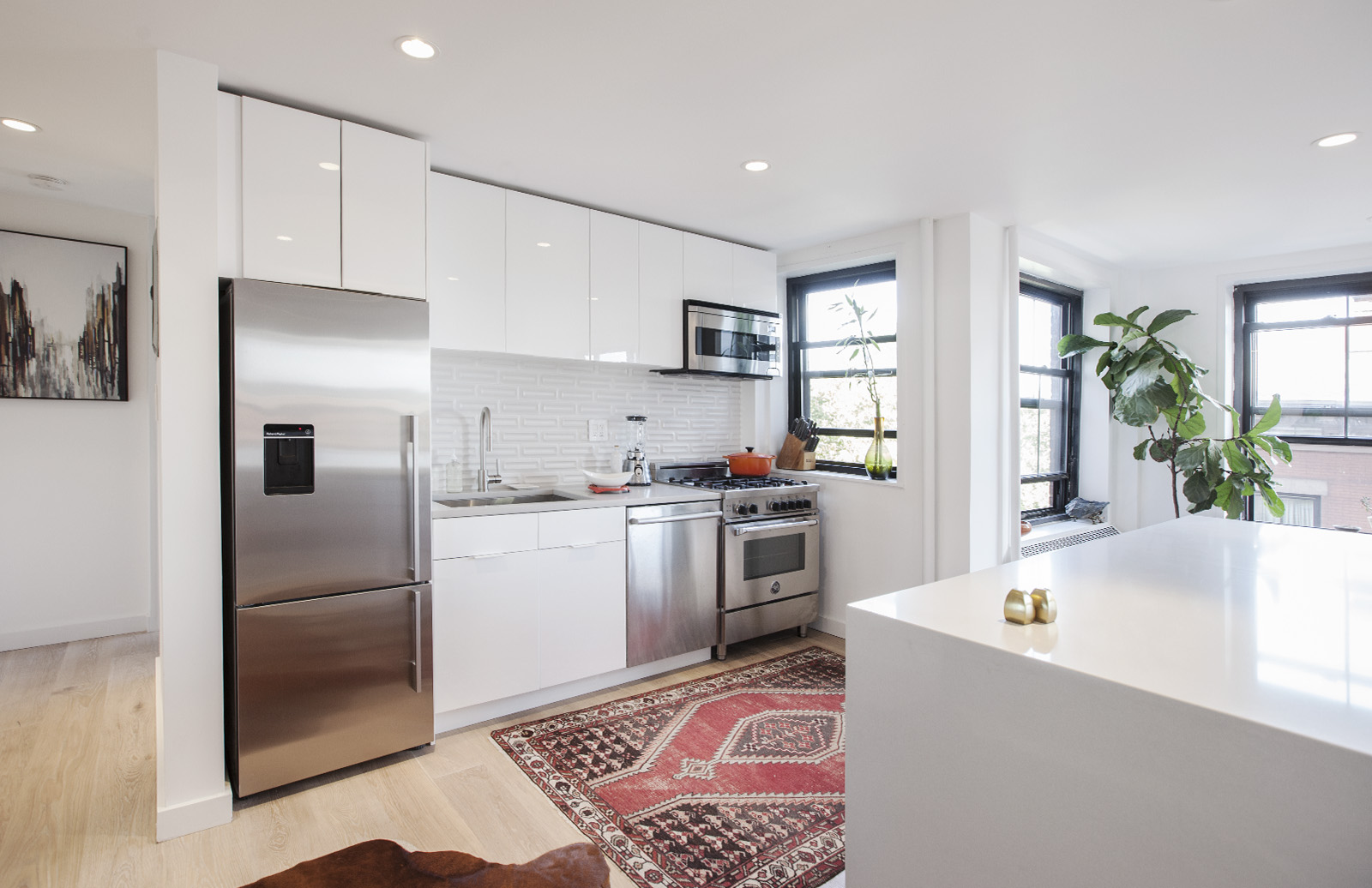 Bright white kitchen with long counter run and large island; plan fits holiday hosting, with prep space and a clear gathering spot for guests.