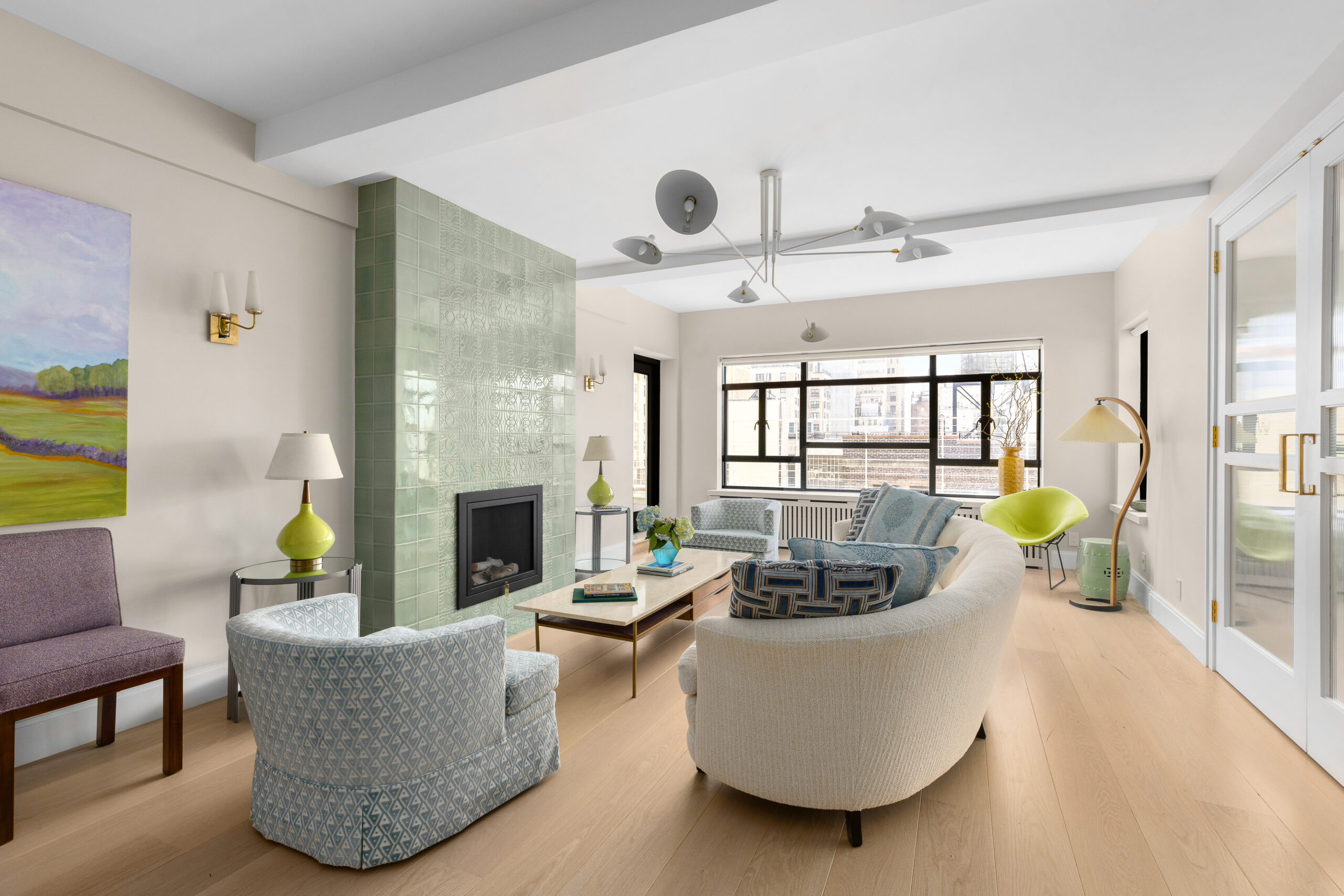Renovated city living room with updated flooring, modern lighting, and reworked seating layout that improves flow, comfort, and everyday usability.