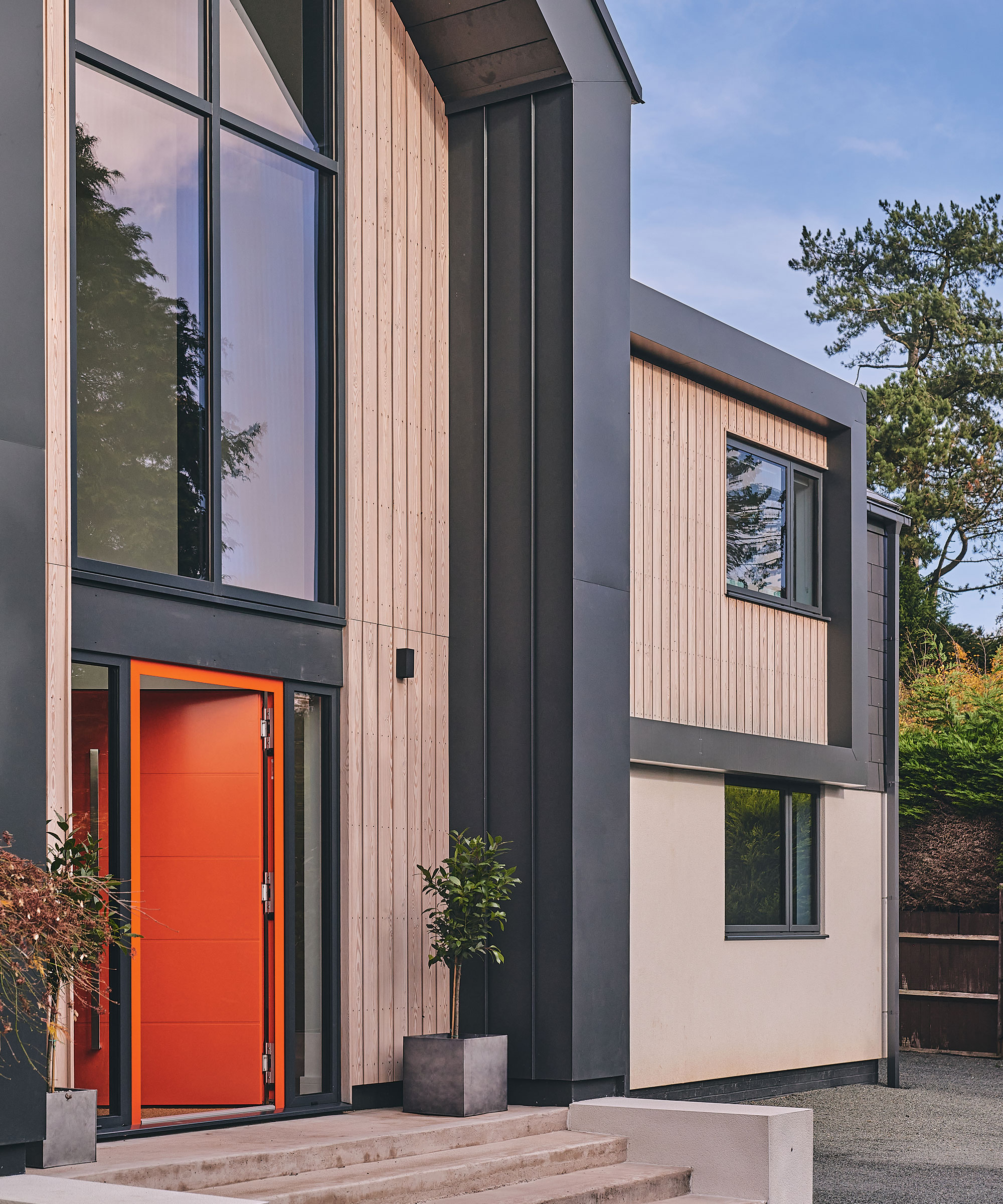 exterior of a modern self-build with timber cladding and bright orange front door
