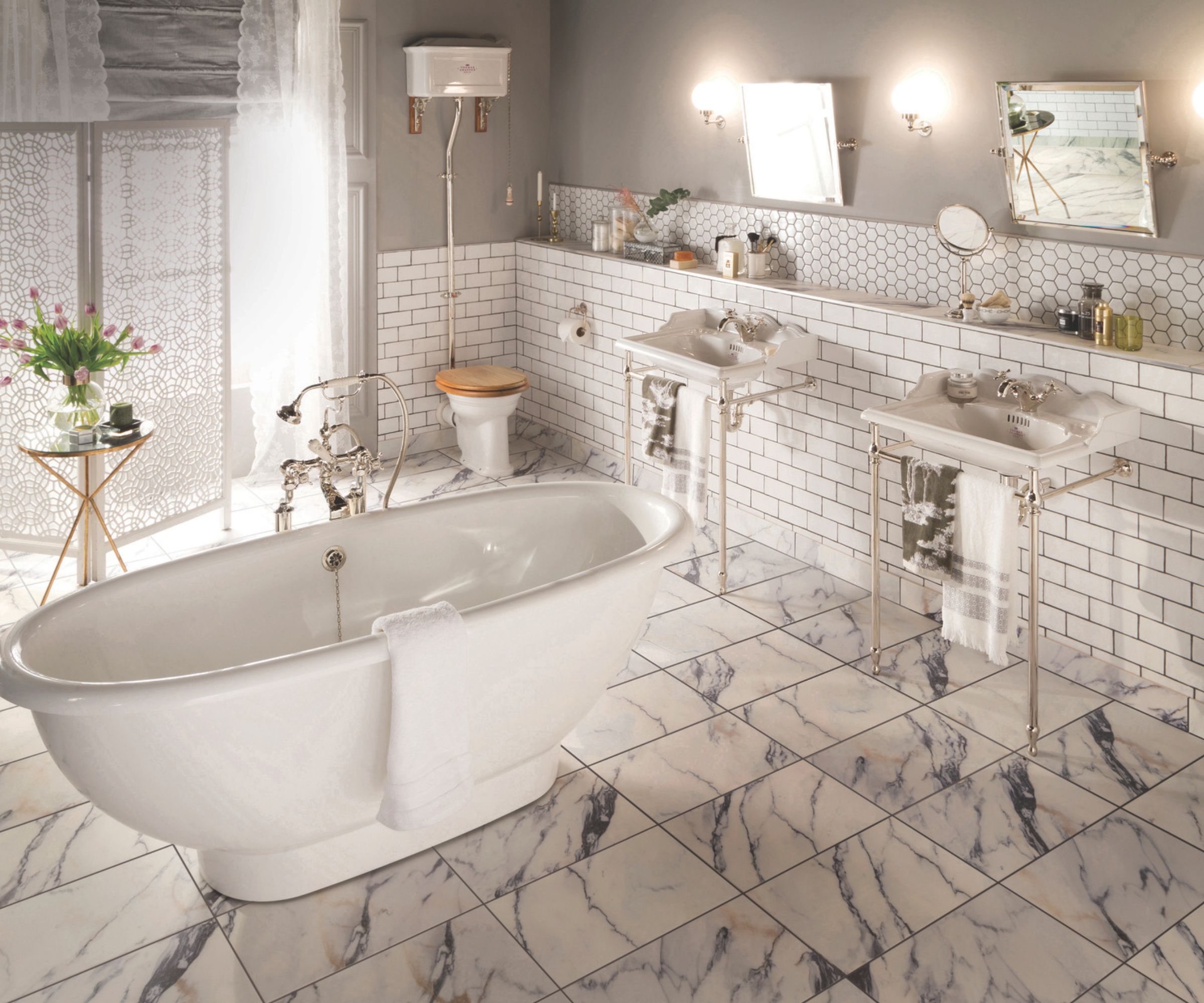 A classic bathroom with a freestanding roll-top bath, twin pedestal basins, metro wall tiles and marble-effect flooring for an elegant, timeless look.