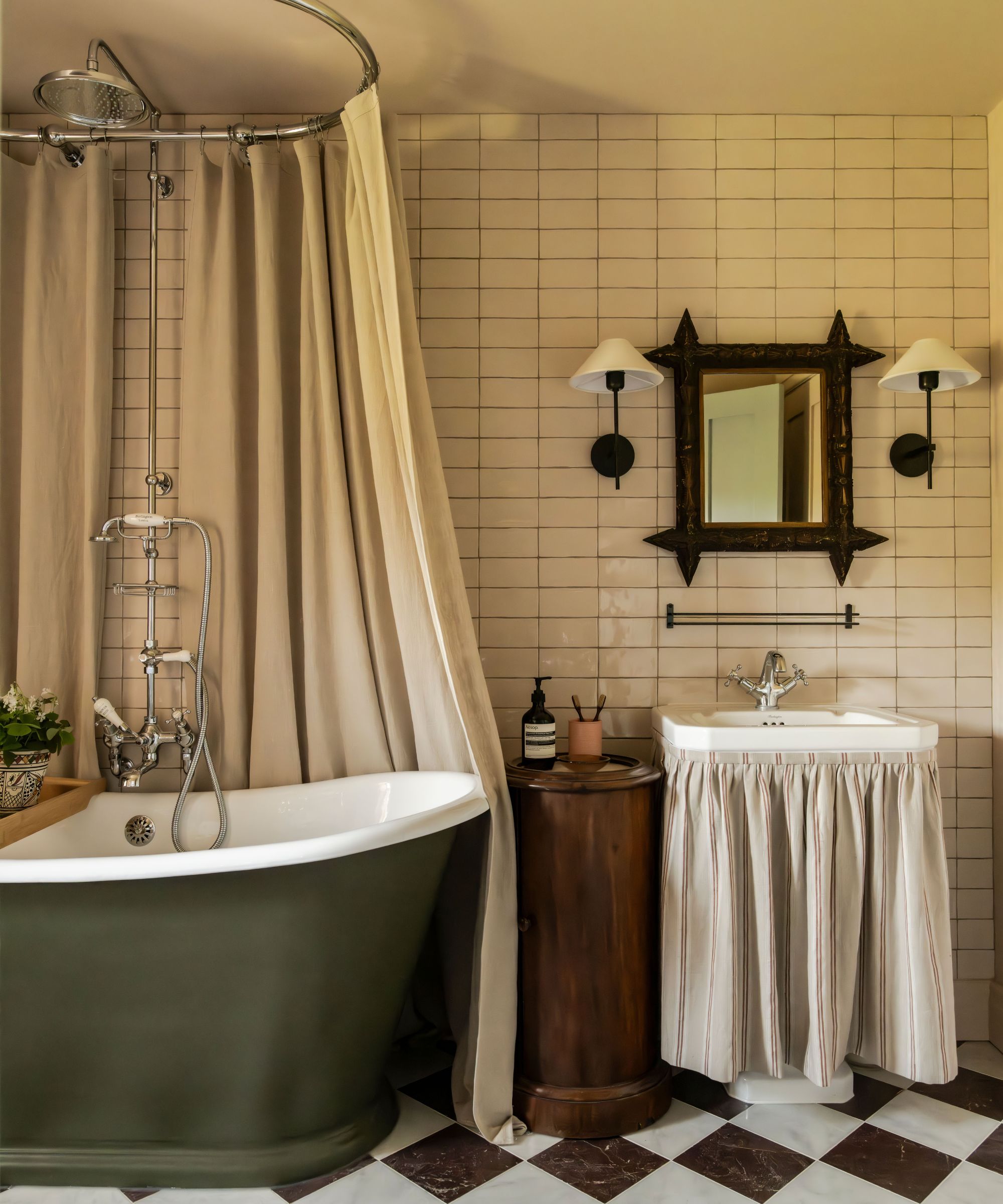 A characterful bathroom with a roll-top bath, fabric sink skirt, tiled walls and vintage-style fittings, blending charm with relaxed elegance.