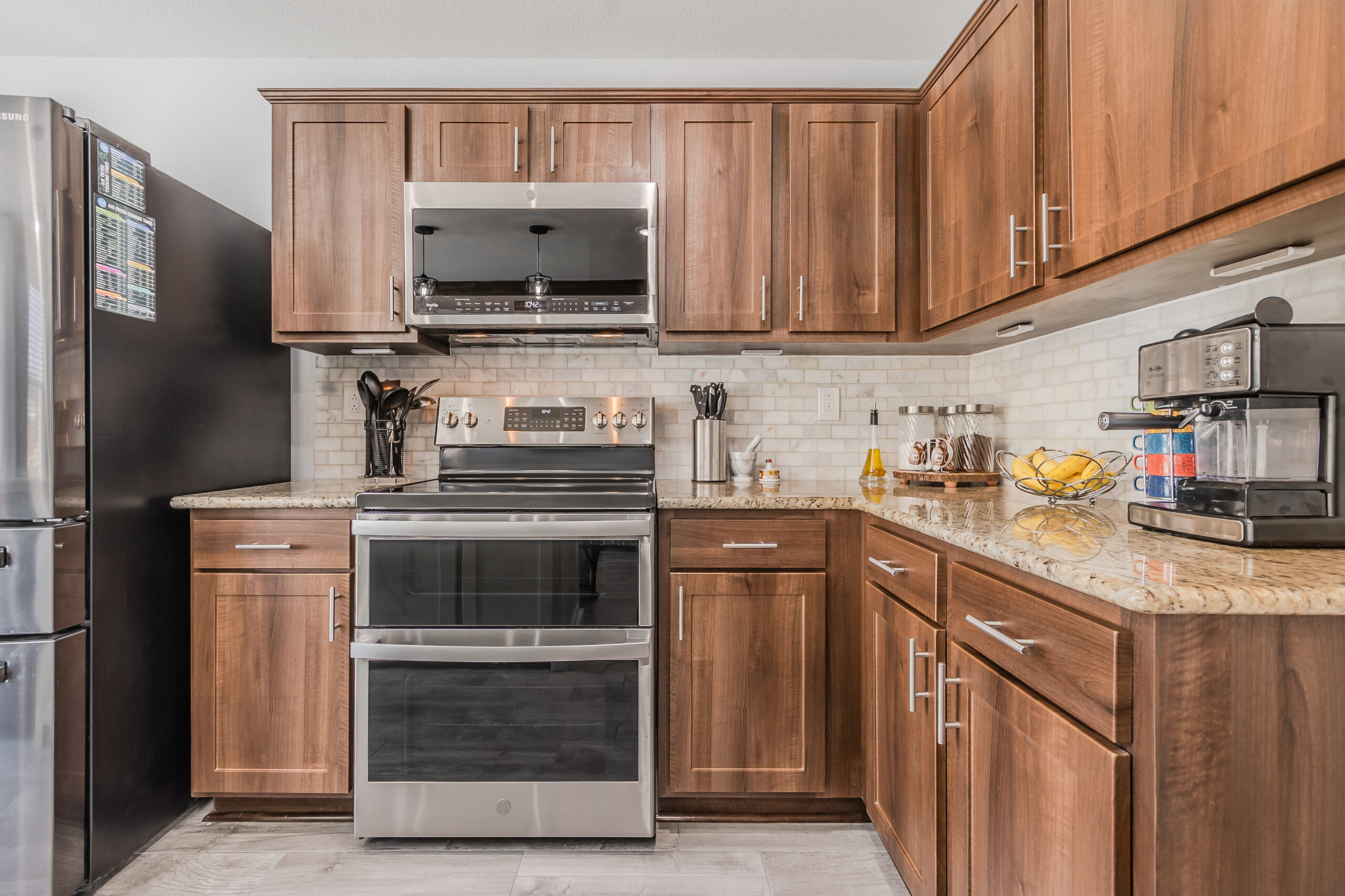 Kitchen with wood Shaker cabinets, stove with hood, and tiled kitchen backsplash