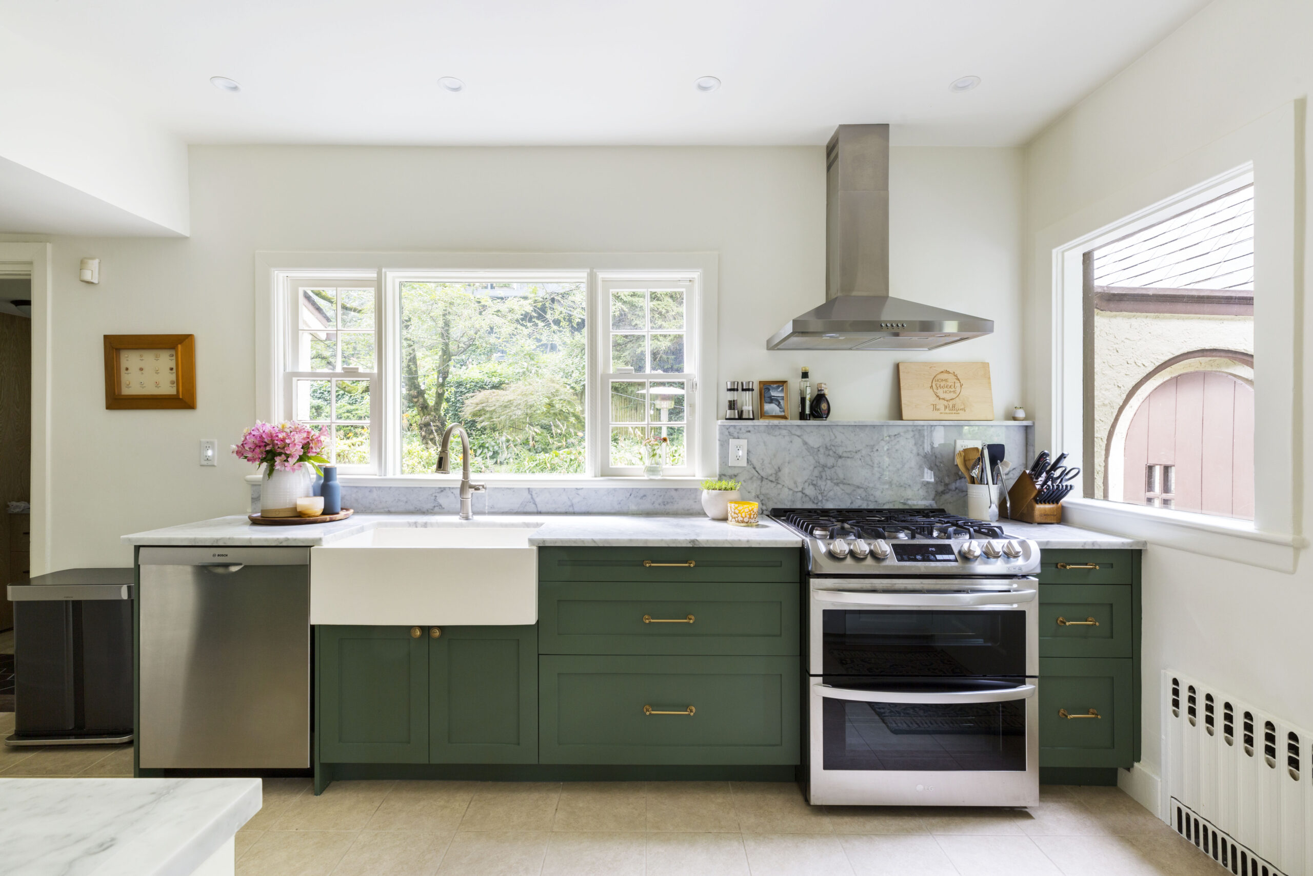 Kitchen with deep green Shaker cabinets, range with hood, counter fridge, and white walls